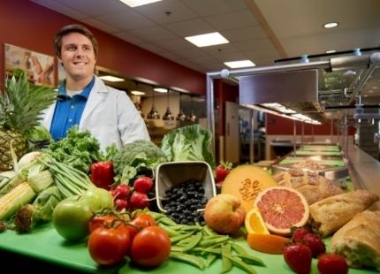 Food and Nutrition student wearing lab coat standing with healthy food items