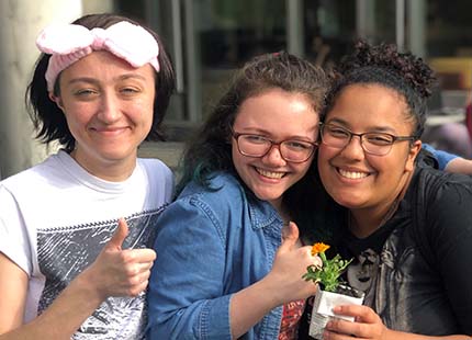 three students holding a flower
