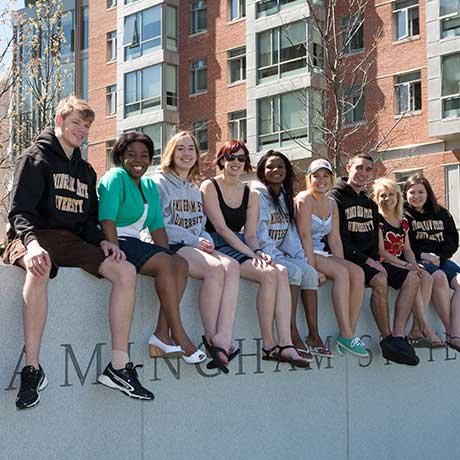 Smiling students sitting on Framingham State University wall on Accepted Students Day